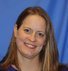 An image with a woman with long blonde hair smiles at the camera with a blue background