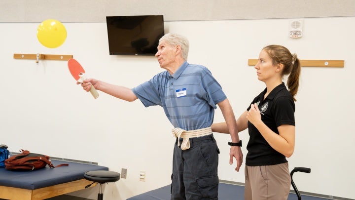 Physical Therapy activity with adult using paddle and balloon