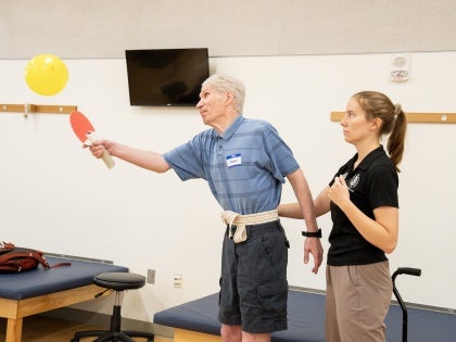 Physical Therapy activity with adult using paddle and balloon