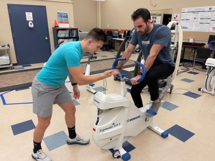 Student in exercise science program taking measurements with person on spin bike